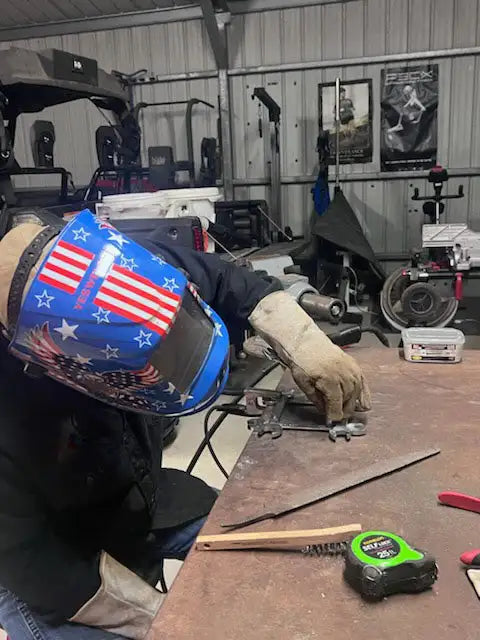 Patriotic welding helmet with stars and stripes design, made of metal.